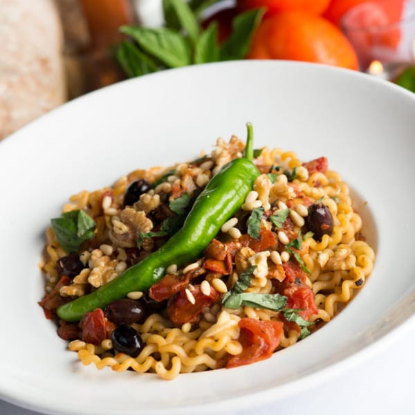 Zuccarelli's Italian pasta dish with tomatoes, olives, nuts, and a green pepper garnish.